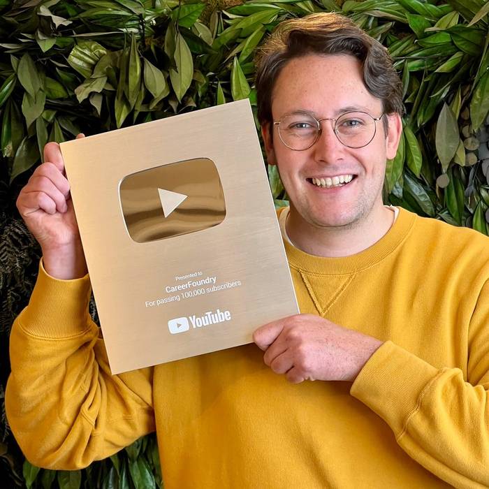 Calum holding the Silver Play Button from taking CareerFoundry’s YouTube channel past 100,000 subscribers