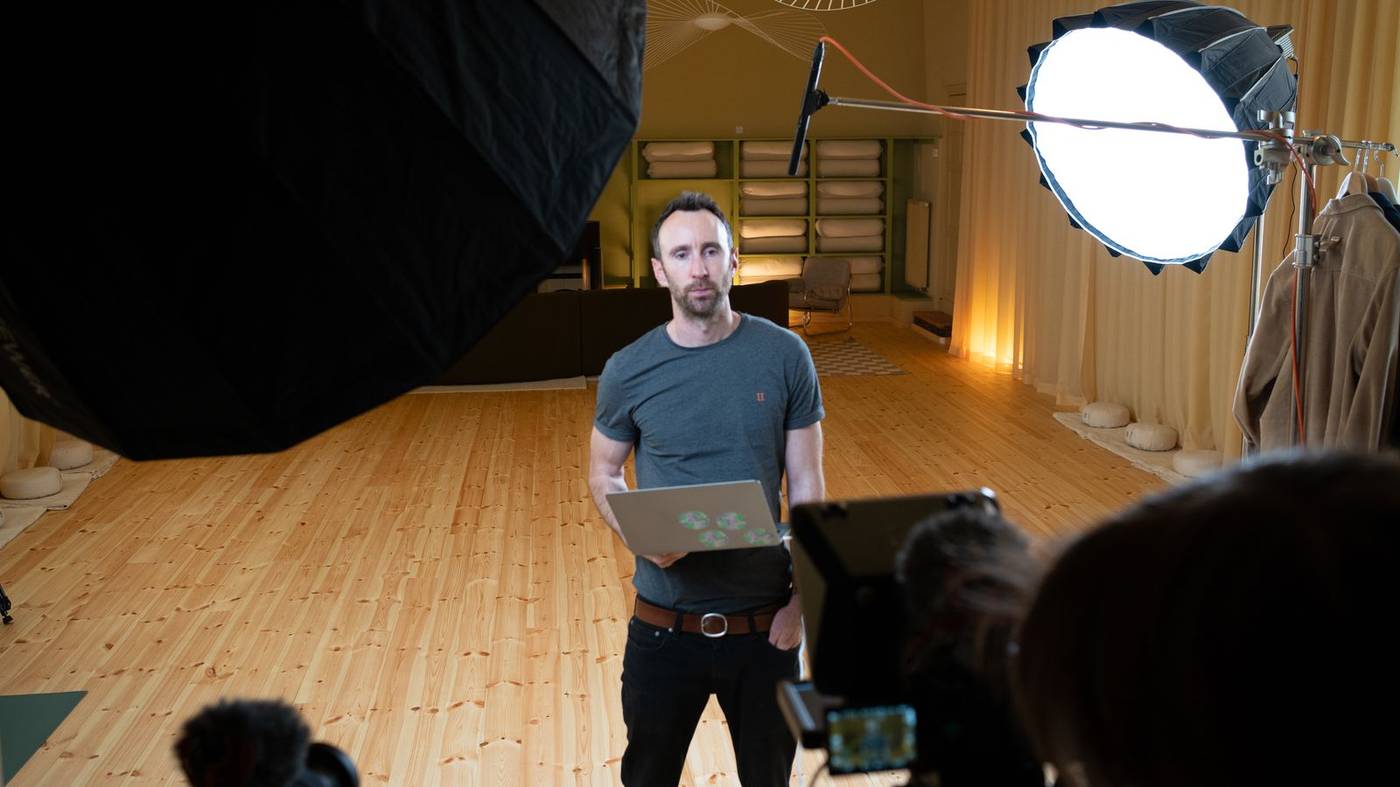 Ed teaching on the yMBA set — softbox, camera, warm studio